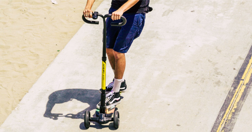 Close up of a young man riding a Swagger Cali Drift three-wheeled electric scooter