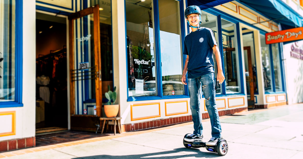 Smiling kid wearing helmet and riding a Swagboard Twis hoverboard