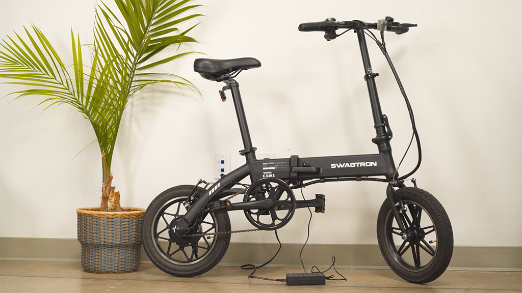 The EB5 Pro electric bike, standing on its kickstand while connected to its charger