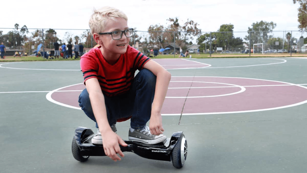 Young teen squatting on his swagBOARD T5 Classic hoverboard.
